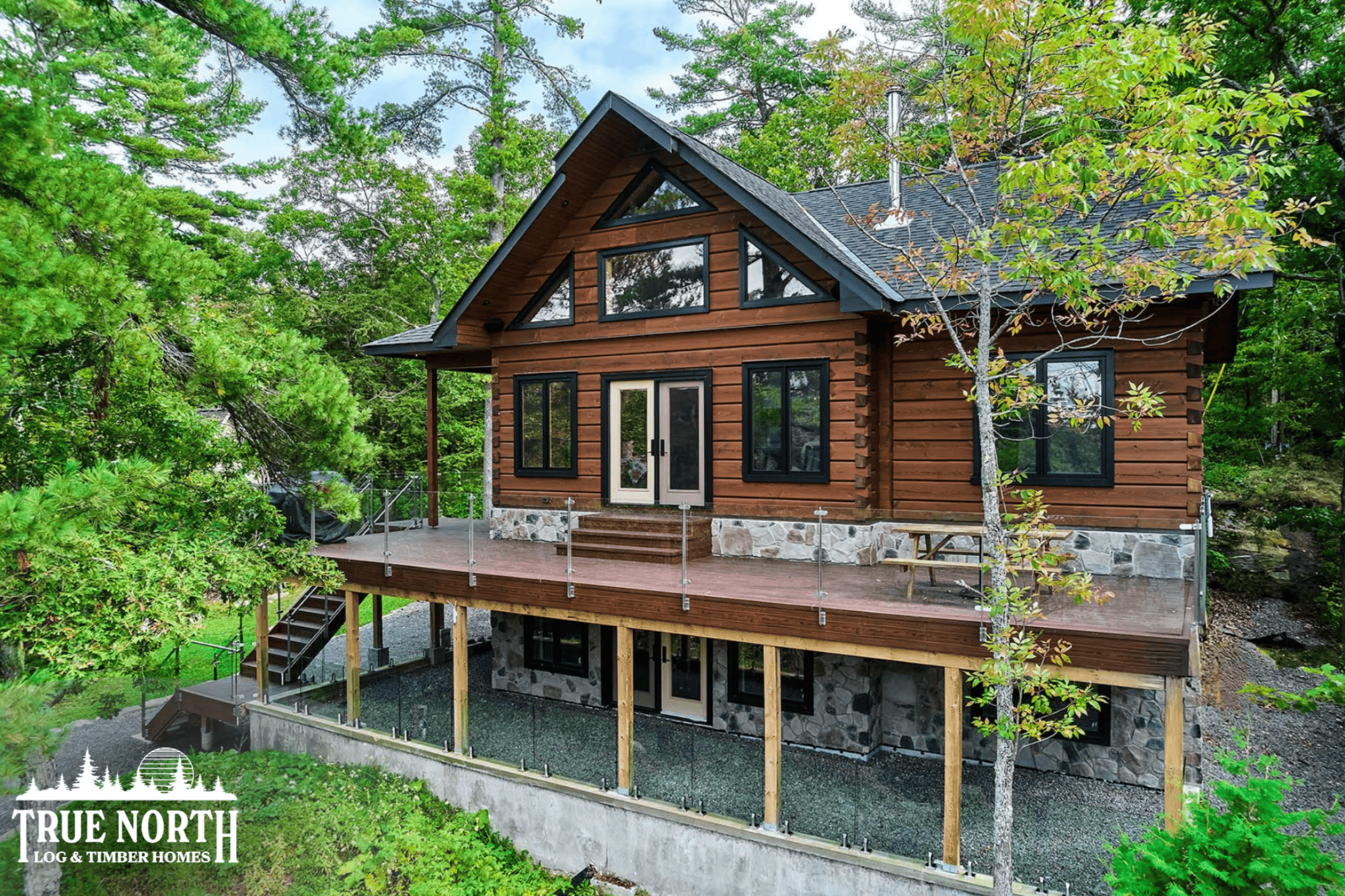 This is the Moore Residence, a custom True North Log & Timber Home with stunning lake views. This home is nestled in the serene forest surroundings. 