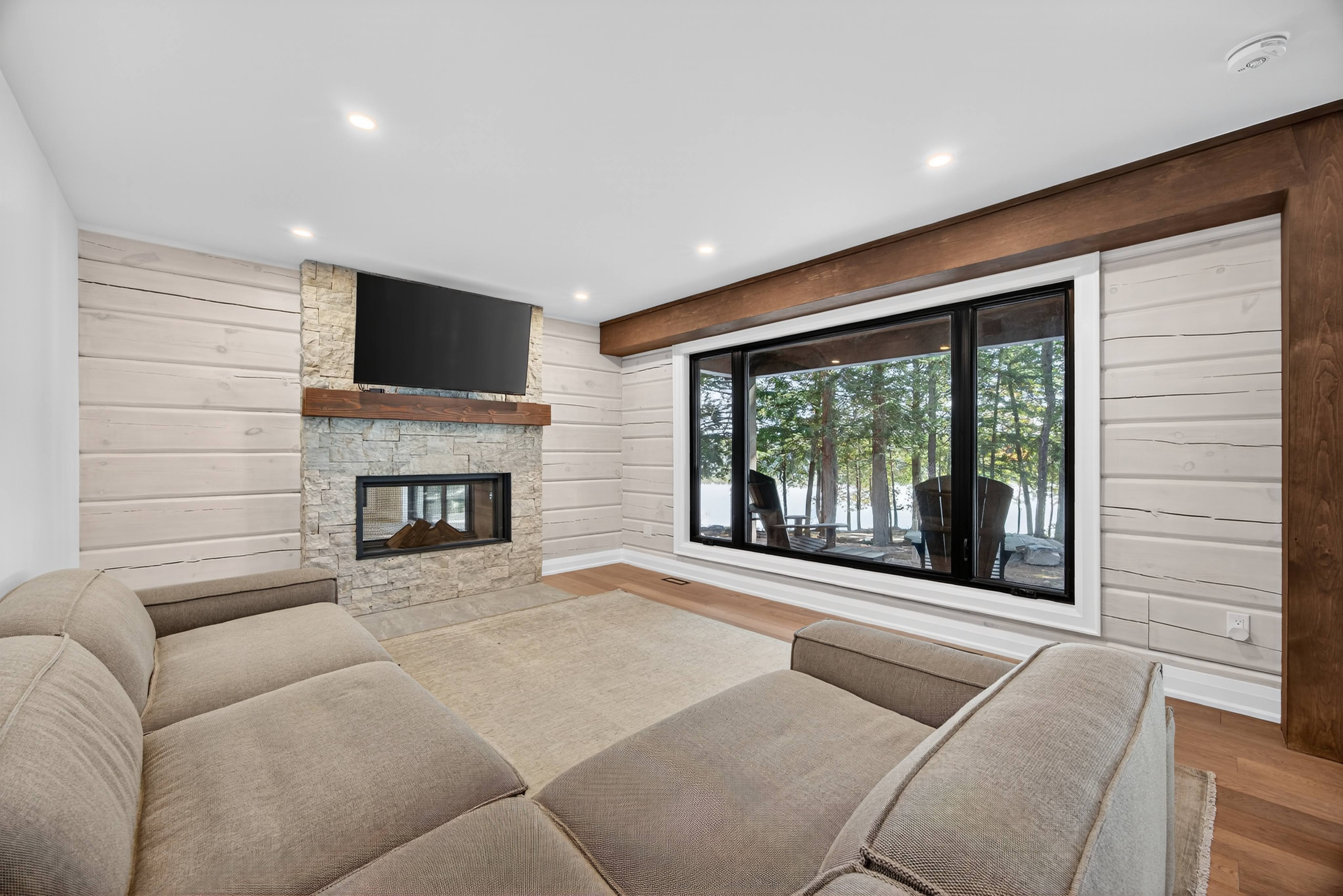 The living room of a log home that was remodeled by Legacy North Construction Management. This cottage uses timber beams to create clean and continuous lines through the open-concept living and dining room.