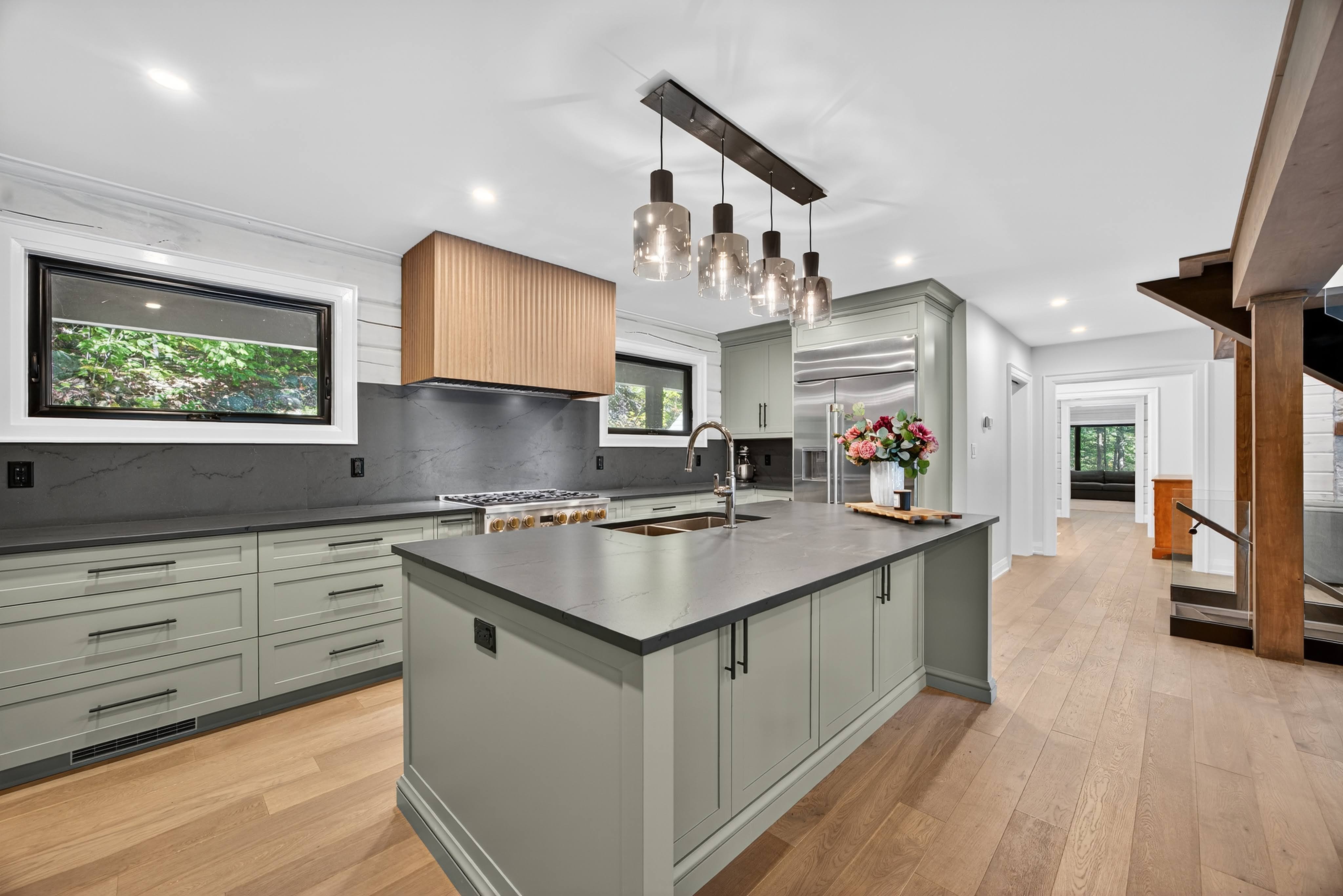 The kitchen of a log home that was remodeled by Legacy North Construction Management. This project focused on modern fixtures like matte black hardware, natural textures of wood and stone, and a neutral colour scheme to create a timeless and sophisticated environment.