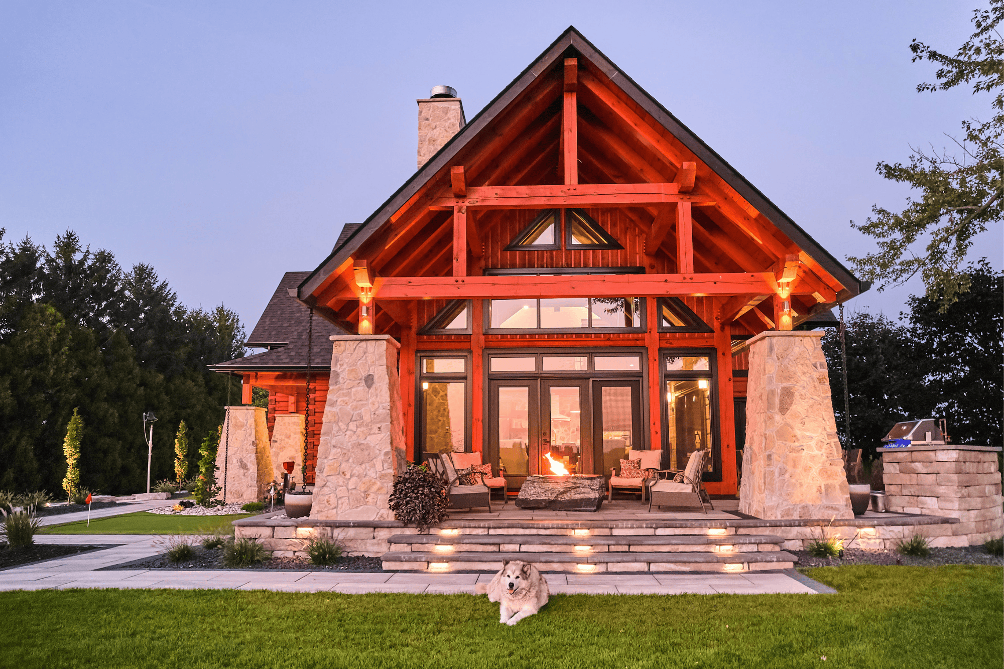 The patio of True North Log & Timber Homes’ award-winning Northern Escape. This home uses black aluminum window and door frames, and bold stone pillars to balance the warmth of the log and timber. This careful balance transforms this stunning outdoor seating area.
